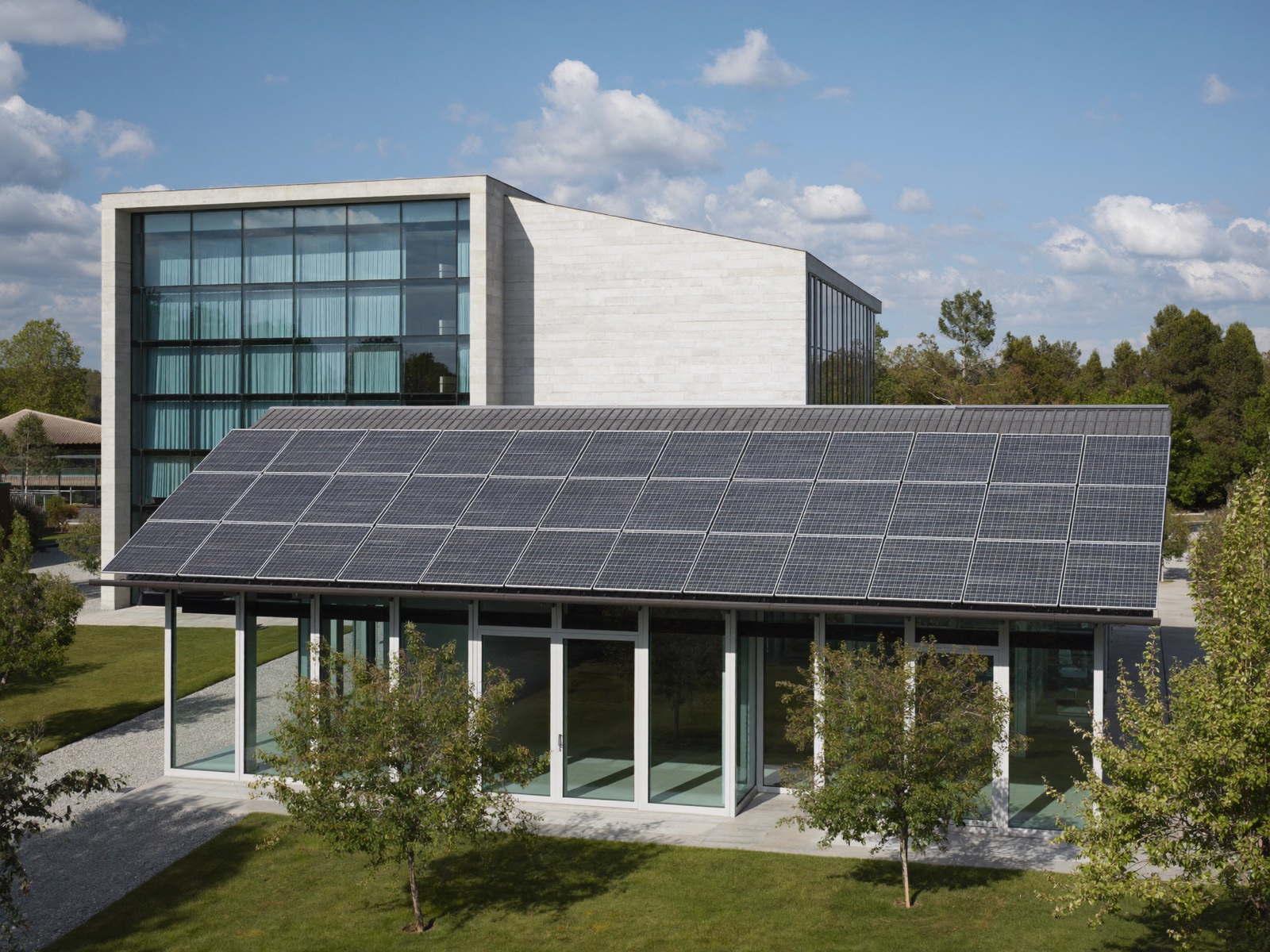 Si&egrave;ge d'entreprise moderne au toit photovolta&iuml;que, entour&eacute; d'arbres